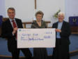 Eileen Davis (centre) presenting Rev M Jones and Michael Carr with the cheque.